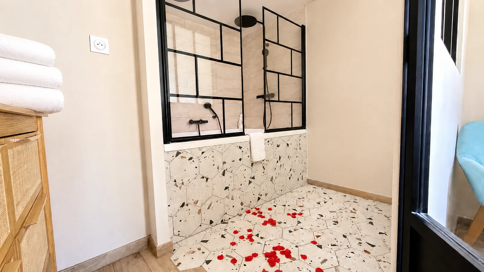 Baignoire balnéo derrière sa verrière, pétales de roses au sol