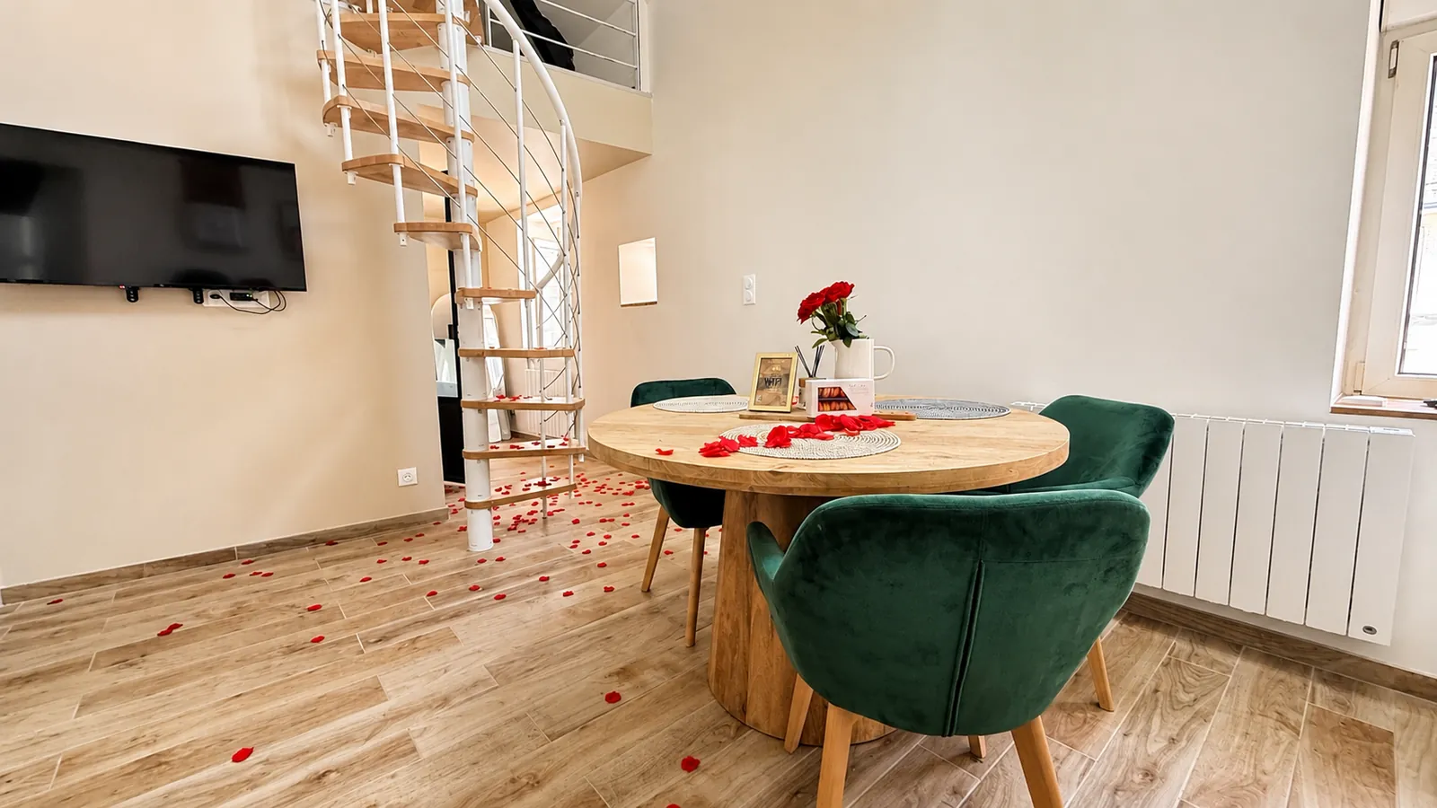 Salon avec table ronde, fauteuils verts et pétales de roses
